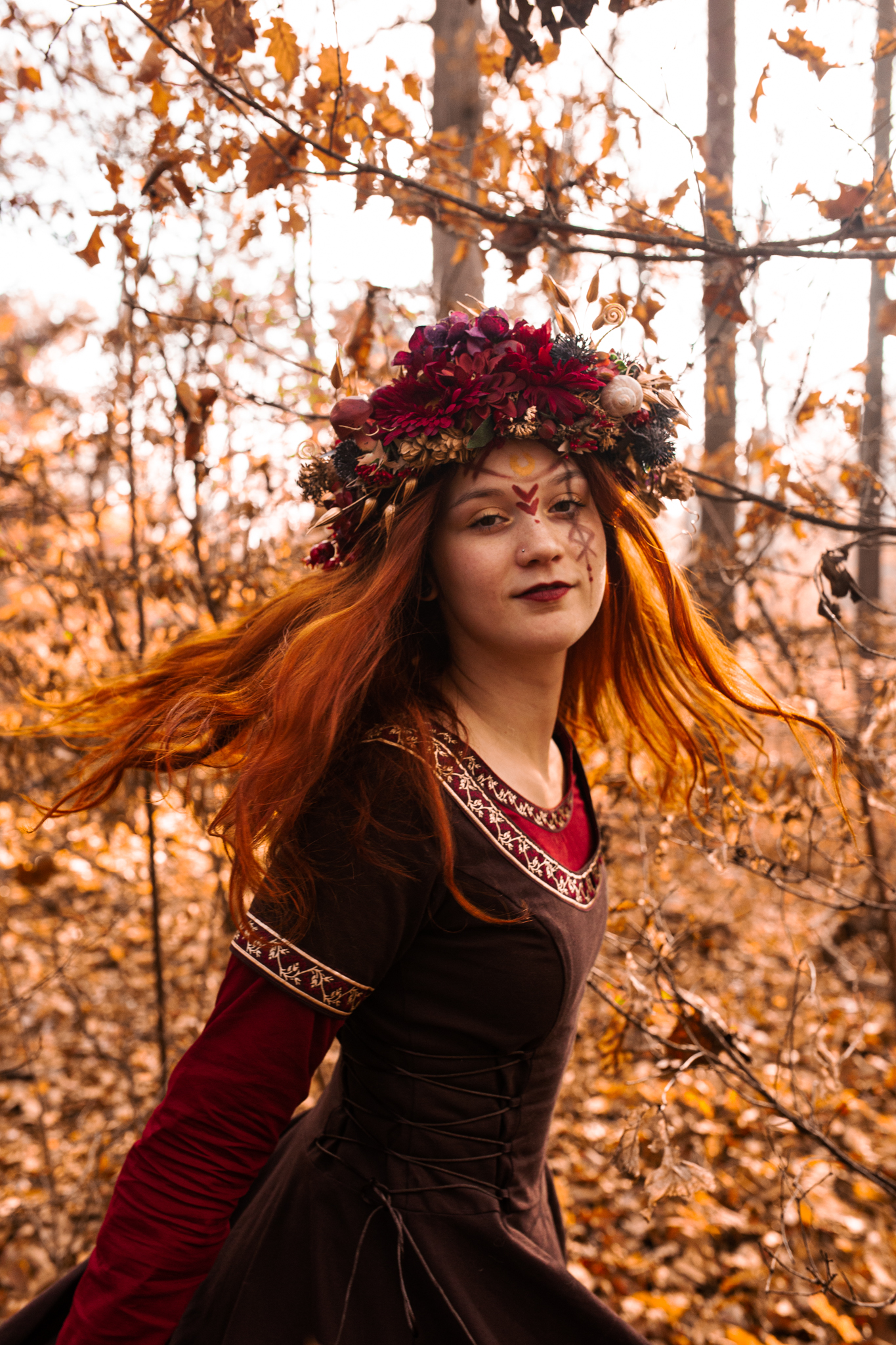 Krásná zrzavá žena ve fantasy šatech v podzimní krajině.